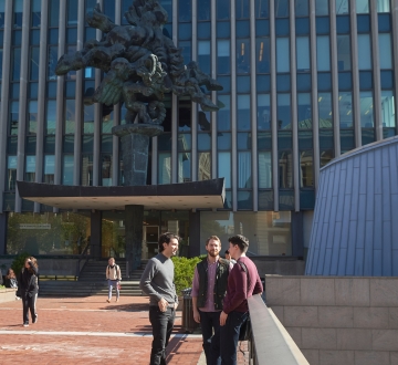 Three students talk on Revson Plaza next to the Pegasus statue