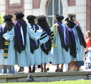 A group of 6 graduates in regalia outside at graduation