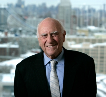 Jack Weinstein portrait, smiling in front of a cityscape