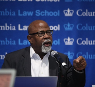 Columbia Law Professor Kendall Thomas in glasses and white shirt in front of mircrophone