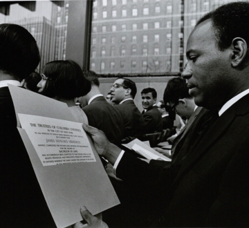 Seated James Meredith looks at diploma at graduation