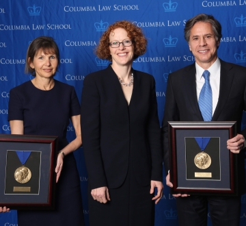 Alison S. Ressler '83 and Antony Blinken '88 hold up their Medal for Excellence awards with Dean Gillian Lester