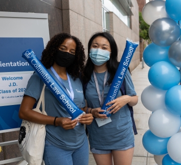 Two women in blue shirts next to blue and white balloons