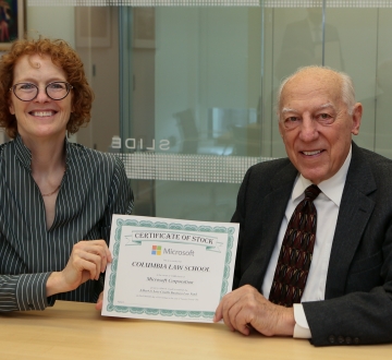 Woman and man, seated side by side, hold stock certificate