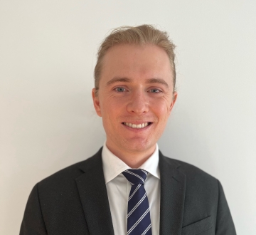 Male student in a suit and blue tie, smiling