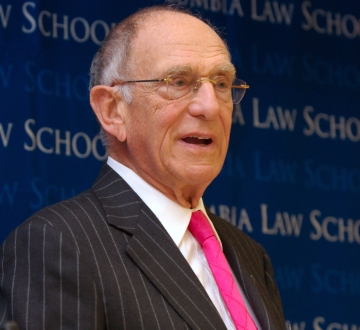 Man with glasses in pinstripe suit and pink tie