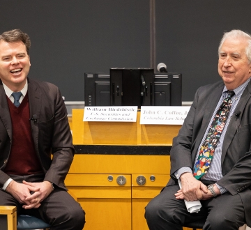 Two men seated, smiling 