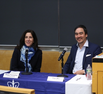 Woman and man sitting at panel table, smiling. 