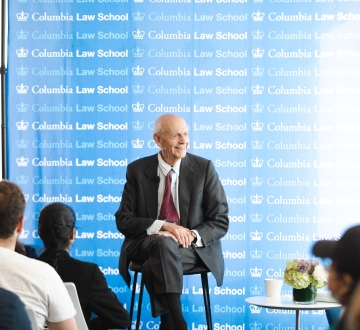 Man in suit in front of Columbia Law School banner