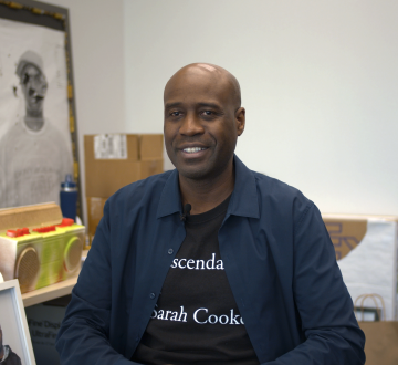 Man wearing a blue collared shirt sitting in front of artwork