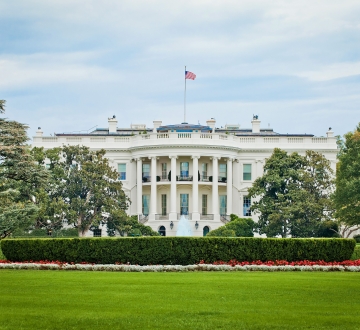 The White House with a blue sky behind and a green lawn in front