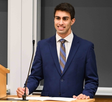Akesh Shah stands behind a podium.