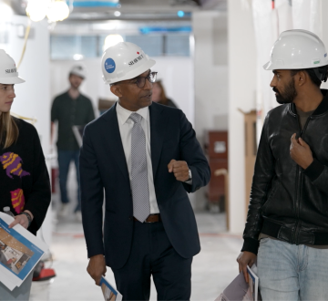 Two. men and a woman in hardhats walking and talking