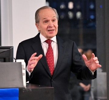 Man in suit and tie gesturing at podium