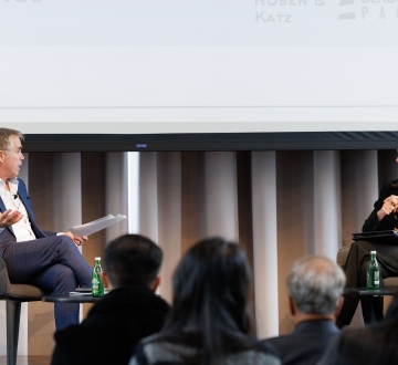 Man interviewing woman, both seated onstage