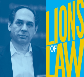 Dark haird man in suit without tie with Lions of Law graphic