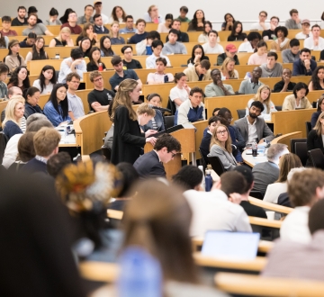 A student at the podium surrounded by fellow students, faculty, and family watching the 2026 Harlan Fiske Stone Moot Court finals.