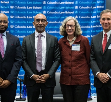 Justice Raheem L. Mullins in suit, Columbia Law Dean Daniel Abebe in suit and tie, Judge Debra Livingston in brick-colored jacket, and Judge Michael A. Chagares in suit and tie all standing in front of a Columbia Law School banner