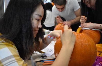 A student carves a pumpkin.