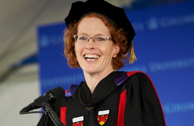 Dean Lester smiling and wearing academic regalia at the podium during the 2019 graduation ceremonies.