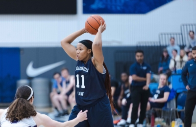 A Columbia Law student holds a basketball overhead.