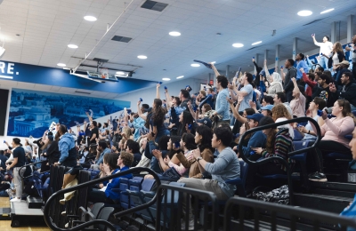 Spectators in bleachers cheer at the 2023 Dean's Cup basketball game.