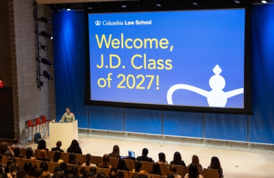 Woman at podium in front of large screen