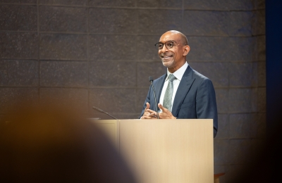 Man in glasses wearing suit speaking at podium