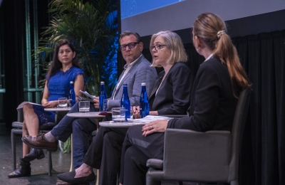 Panel of three women and one man on stage discussing. 