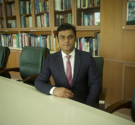 Bhagwati Fellow Devranjan Mishra in suit and tie sitting at conference table