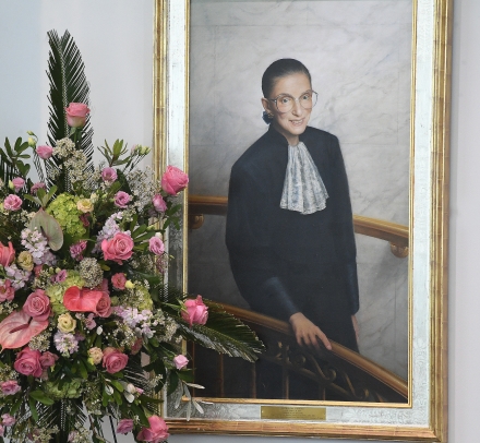 Flowers in front of a portrait of Ruth Bader Ginsburg.