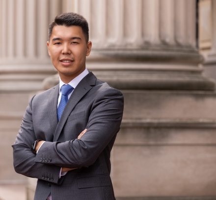 Man with short dark hair in dark great suit and blue tie