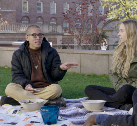 Three students sitting on a lawn talking