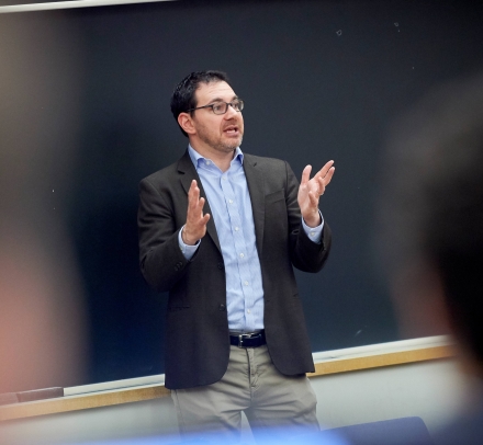 Dark haired man speaking and gesturing 
