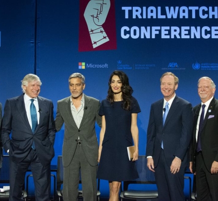 6 men in suits flank a woman in black dress