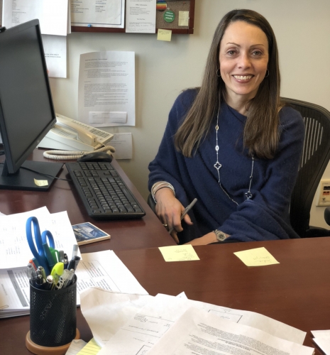 Dean Erica Smock of SJI sits at her desk in her office and smiles.