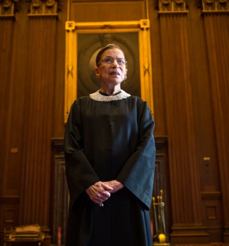 Ruth Bader Ginsburg wearing her justice robes in front of a portrait