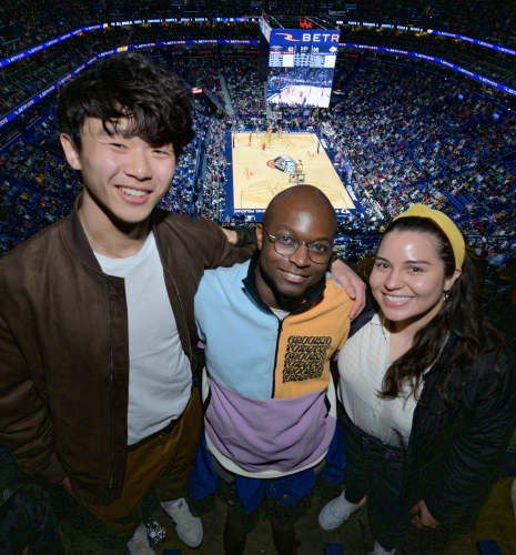 Three people in the top rows of a basketball arena