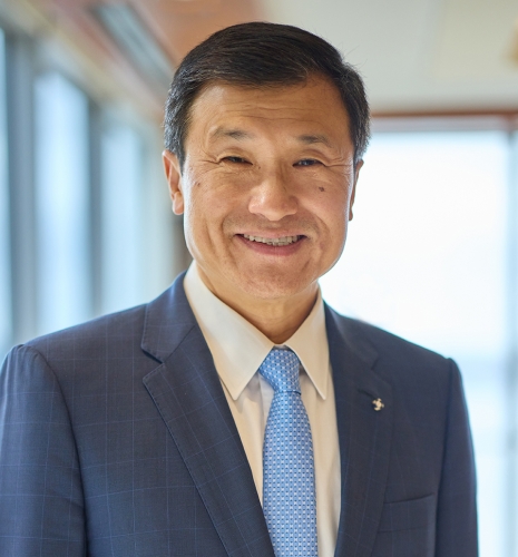 Headshot of a man wearing a blue jacket, white shirt, and blue tie