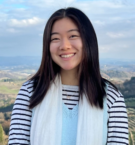 Vivian Zhao smiles in front of a hilly landscape.