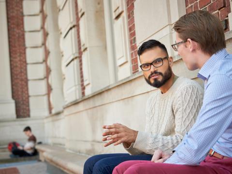 Two students sit on a stone bench