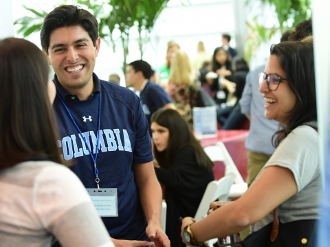 A student wearing a Columbia sweatshirt smiles at another student.