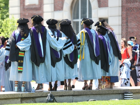 A group of 6 graduates in regalia outside at graduation