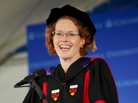 Dean Lester smiling and wearing academic regalia at the podium during the 2019 graduation ceremonies.