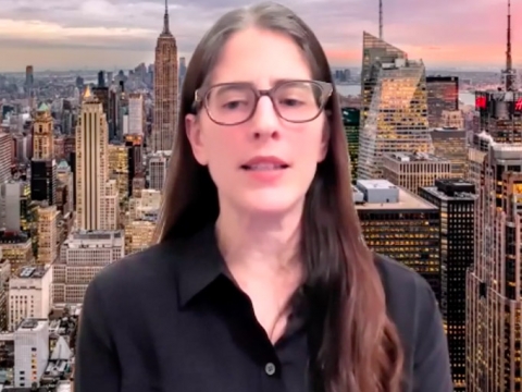 Professor Christina Ponsa-Kraus speaks in front of a backdrop of the New York skyline
