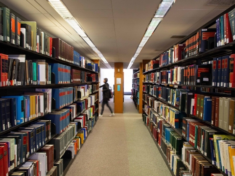 A student walks past a shelf of books in the Diamond Law Library