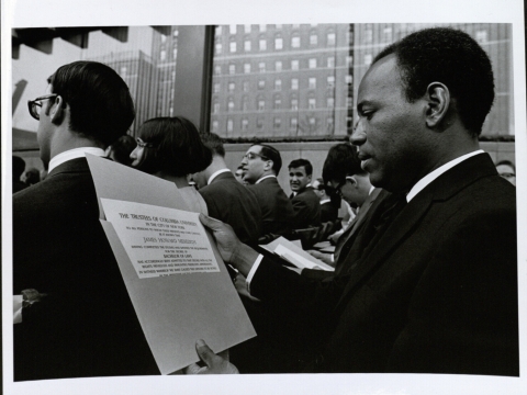 Seated James Meredith looks at his diploma at 1968 graduation 