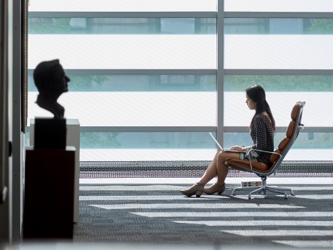 A student sits in Jerome Greene Hall with her laptop.