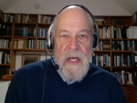Michael Graetz wearing a headset and microphone in front of a wall of bookshelves