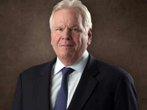 White-haired man in black suit with blue tie